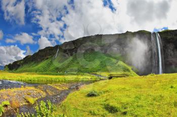 The warm summer day in Iceland. Selyalandfoss waterfall and picturesque flowering fields and streams
