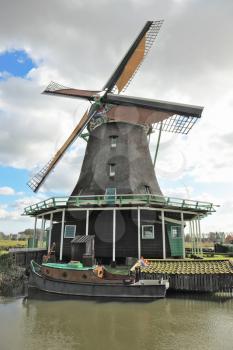 The village- museum in Holland. A picturesque windmill, the channel and ancient rural lodges with red roofs
