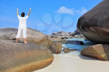 Thailand. Gorgeous beach on the Similan Islands. Middle-aged woman dressed in white doing yoga. 
Pose Blessing of the Sun