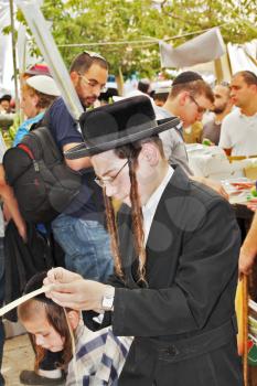 JERUSALEM, ISRAEL - SEPTEMBER 18, 2013: Young religious Jew with long sidelocks carefully chooses ritual plant - myrtle for Sukkot.