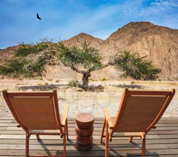 Two convenient chaise lounges and small table stand for tourists. Walking route on  picturesque Black canyon