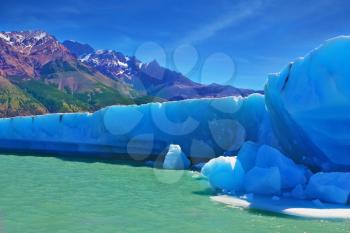 Ices and sun of Patagonia. White-blue huge icebergs float near a ship board. Excursion by tourist motor ship on Vyedm's lake