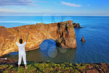 Cape Dirkholaey in the south of Iceland. The enthusiastic woman- tourist welcomes the rock - elephant