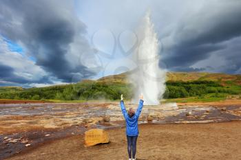 Woman -turist delighted geyser Strokkur. High column of hot water and steam . Gushing geyser Strokkur. 