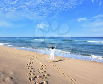  Huge beautiful beach on the Atlantic coast. Middle-aged woman dressed in white doing yoga. The seaside resort of Sintra