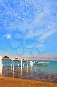 The Dead Sea, the umbrellas waiting for tourists. Beautiful sunny day at a beach resort