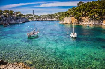 The fjords between stony coast. White sailing yachts wait for the owners.  National Park Calanques on the Mediterranean coast