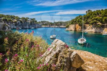 White sailing yachts in the sea fjord. The picturesque gulf with turquoise water at coast of the Mediterranean Sea. National park of Calanques in Provence