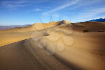 Woman in striped shirt photographing sand waves. Mesquite Flat Sand Dunes. Hot autumn in Death Valley, California