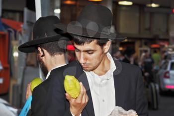 BENE - BERAK, ISRAEL - SEPTEMBER 17, 2013: A young religious man - Jew closely examining citrus - fruit for the holiday of Sukkot. The traditional holiday bazaar before Sukkot