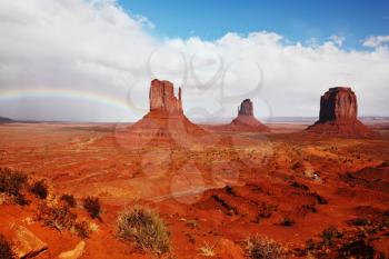 Red stone desert Navajo, USA. Isolated rocks - mitts intersect with the beautiful rainbow. 