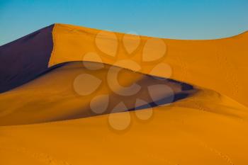The soft curves of orange sand dunes. Hot and windy morning in the desert. Hot autumn in Death Valley, California