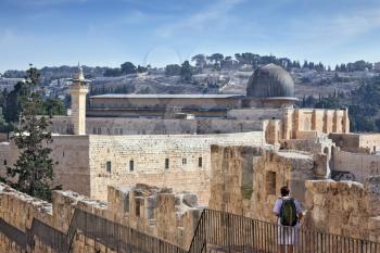 Along the walls of Jerusalem, is a brooding woman- pilgrim with a backpack. In the distance you can see the gray dome of the Al-Aqsa Mosque and the Muslim minaret