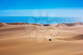 Huge sand dunes moving on the Atlantic coast. Sandwich Harbour - part of Namib-Naukluft National Park. Tourist trip by jeep