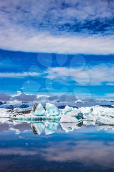  Ice floes and icebergs are reflected in the mirrored water of ocean. Ice lagoon in July. Summer vacation in Iceland