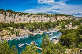 The picturesque fjord with turquoise water at coast of the Mediterranean Sea. National park of Calanques in Provence, between Marseille and Kassis.  White and graceful sailing yachts in the deep sea g