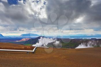 Krafla Lake neighborhood. Summer Iceland. Steam rises above the hot ground. Pipeline to transport hot water