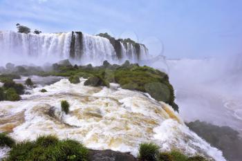 The grand Iguazu Falls on the Brazilian side. Multi-tiered cascades of water roar of lush jungle. Over boiling water swirls fine mist