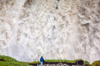 The most powerful waterfall Dettifoss in Jokulsargljufur National Park, Iceland. Elderly woman admires the picturesque spectacle. Huge masses of water cascading into the abyss