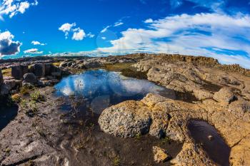 Iceland, Jokulsargljufur National Park. Picturesque small puddle in which is reflected the blue sky. Photo taken fisheye lens