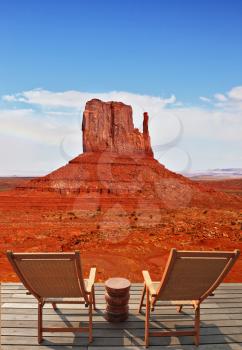 Red sandstone in the valley of the Navajo, USA. Two wooden deck chairs on the platform are to review the rock - mitts