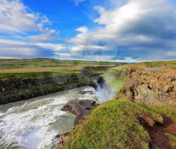 Fantastically spectacular cascading waterfall Gyullfoss. Roaring water glistens on the northern sun. Iceland in the summer