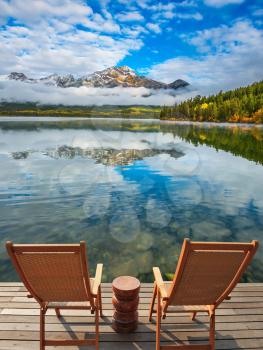 Two deck chairs on a wooden platform.  Pyramid Mountain, Jasper National Park. Concept of  vacation and tourism