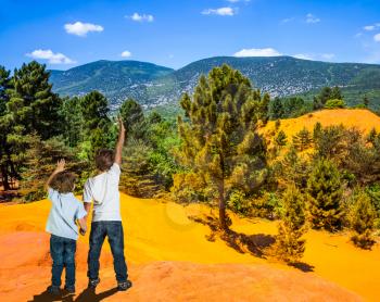  Orange and red picturesque hills in Languedoc - Roussillon. Two boys - brothers of seven and four years admire the magnificent nature