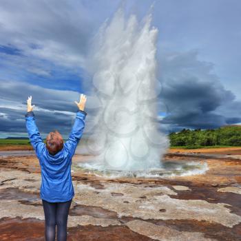 Woman - turist delighted geyser Strokkur. Gushing geyser Strokkur
