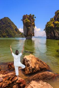 Woman performs yoga pose Tree on the shore of the Andaman Sea. Exotic vacation in Thailand