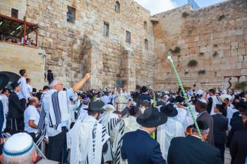 JERUSALEM, ISRAEL - OCTOBER 12, 2014:  The Jews of tallit hold four ritual plants. Morning autumn Sukkot, Blessing of the Kohanim. The area in front of Western Wall of Temple filled with people