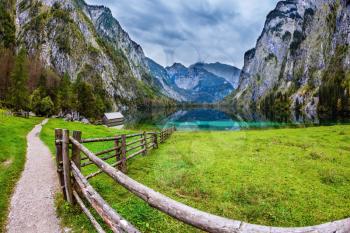 The concept of active tourism and ecotourism. Bavarian Alps. Magic blue lake Obersee and fenced path to it