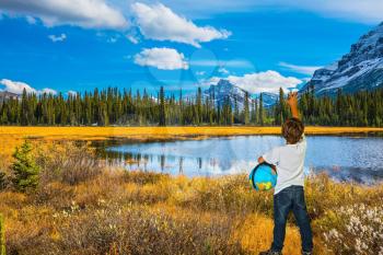 Curious boy with a globe under his arm.  Beautiful nature of the Rocky Mountains of Canada