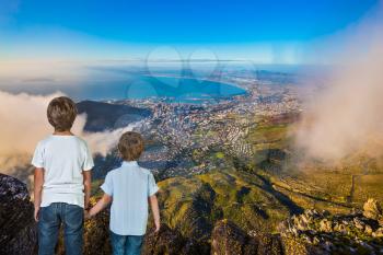 The concept of active tourism and recreation. Travel to Africa. Two boys standing on top of Table Mountain in the clouds
 