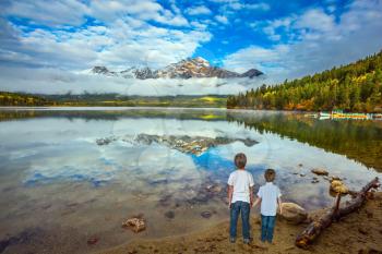 Two boys looking at a lake holding hands. Jasper National Park, Pyramid Lake. The concept of leisure and tourism