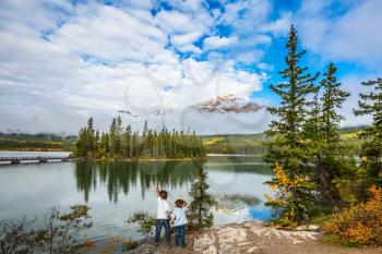 Morning in the Rocky Mountains, Jasper Park. Two boys looking at a lake holding hands. Concept of active vacation and tourism