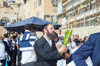 JERUSALEM, ISRAEL - OCTOBER 12, 2014: The area in front of Western Wall of Temple filled with people. Jews wearing tallit hold ritual plants. Sukkot, Blessing of the Kohanim