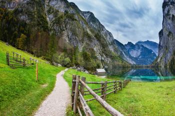 Concept of active tourism and ecological tourism. The Bavarian Alps. The magic blue lake Obersee and the fenced footpath to it