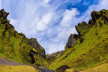 The canyon Pakgil is located among fantastic rocks. On bottom of canyon  fast shallow stream flows. Summer blossoming Iceland. The photo was taken Fisheye lens