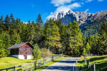 Lovely sunny day. Odle mountain peaks and forested mountains surrounded by green Alpine meadows. Dolomites, Val de Funes valley