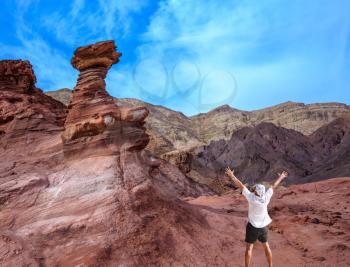 Unique  outcrops  in the mountains of pink sandstone. A lone tourist threw his hands up in delight in Eilat Mountains