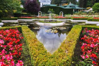 Exquisite fountain among the flower beds. Delightful landscaped and floral park Butchart Gardens on Vancouver Island