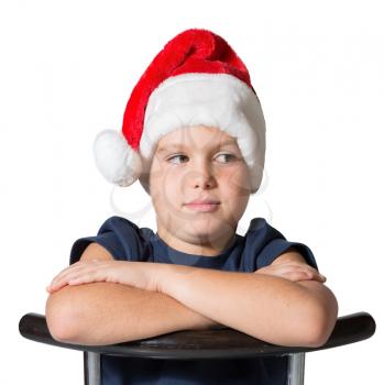 Charming seven-year boy in Santa Claus hat. Photo executed on a white background