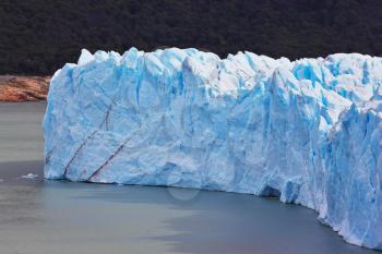 Giant lake Perito Moreno glacier. White-blue ice massif multimeter height rises over the lake