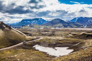 Summer trip to Iceland. The dirt road in a valley surrounded by mountains