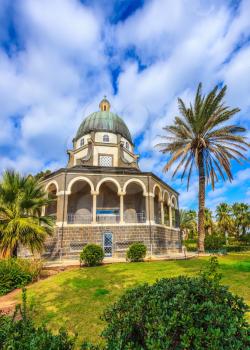 The basilica is surrounded by a gallery with columns. Church Sermon on the Mount - Mount of Beatitudes. Subtle shade of palms and cypresses