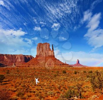 Woman in white performs asana Tree. Navajo Reservation in the US. Red Desert and rocks - mitts sandstone