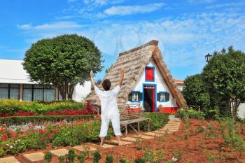 The slender elderly woman in a white suit for yoga carries out an asana Blessing to the sun. A charming rural lodge with a triangular roof