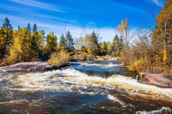 Autumn day. Foam water rapids on the smooth stones of the Winnipeg River. Old Pinawa Dam Provincial Heritage Park. The concept of ecological and adventure tourism