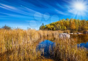 Pale northern sun and yellow autumn grass is reflected in the Winnipeg River. Old Pinawa Dam Provincial Heritage Park. The concept of travel Around the World